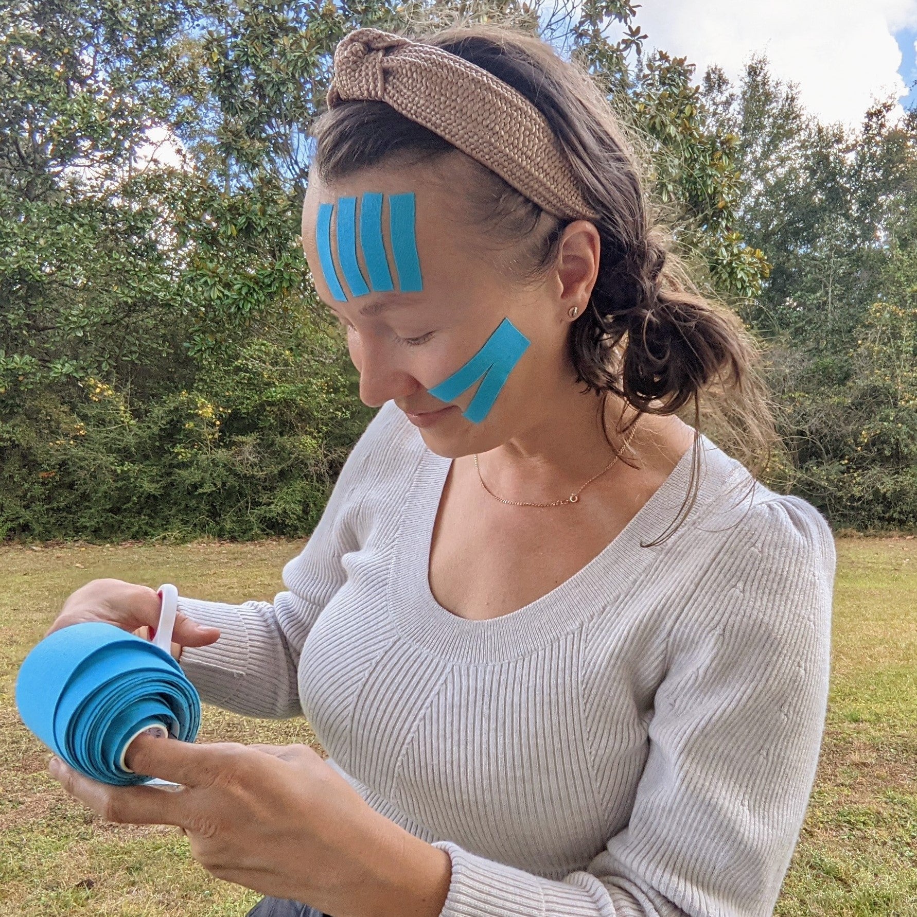 Mila cutting and applying Wild Ice Chrysalis Kinesiology face tape.