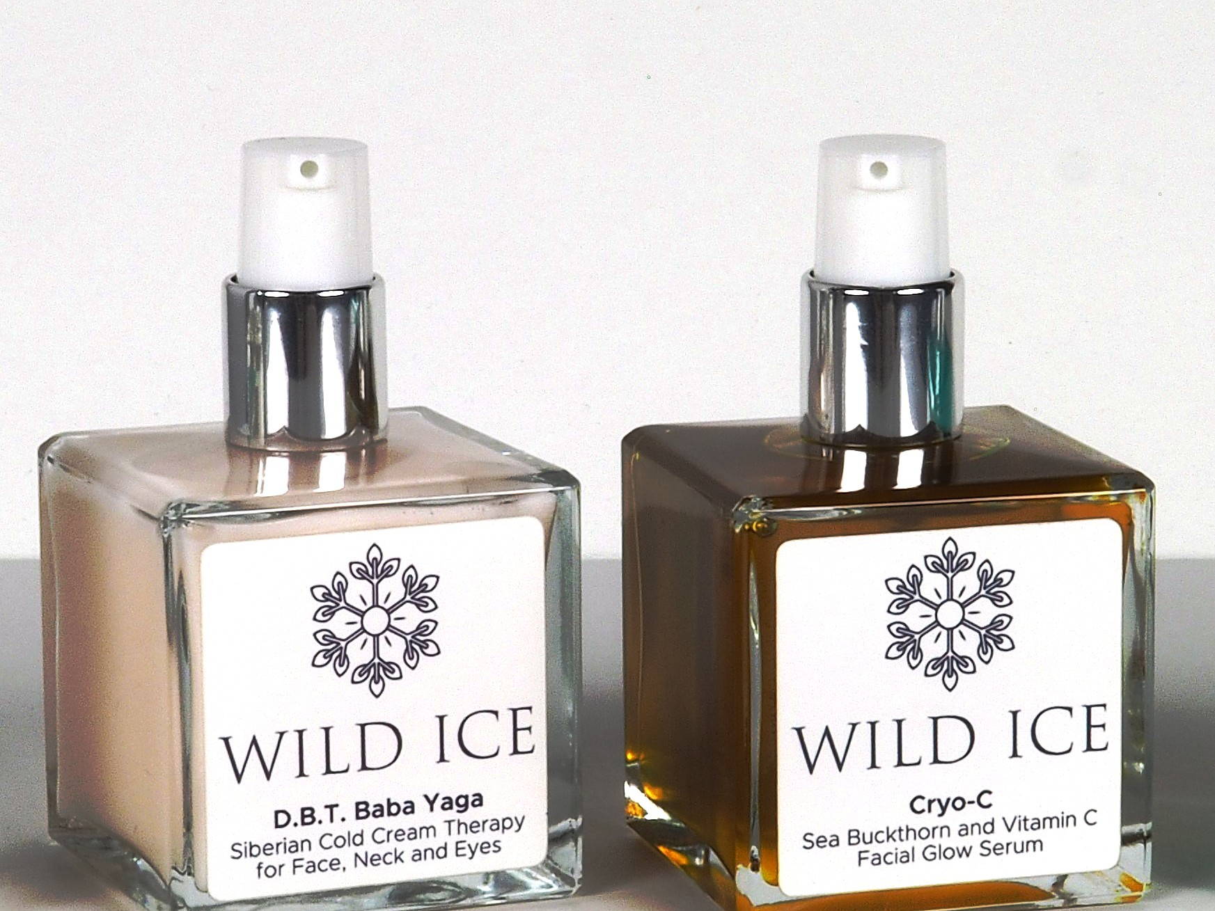 The D.B.T. Baba Yaga cream and the Cryo-C vitamin C serum standing side by side with their pumps uncovered, against a plain pale studio backdrop