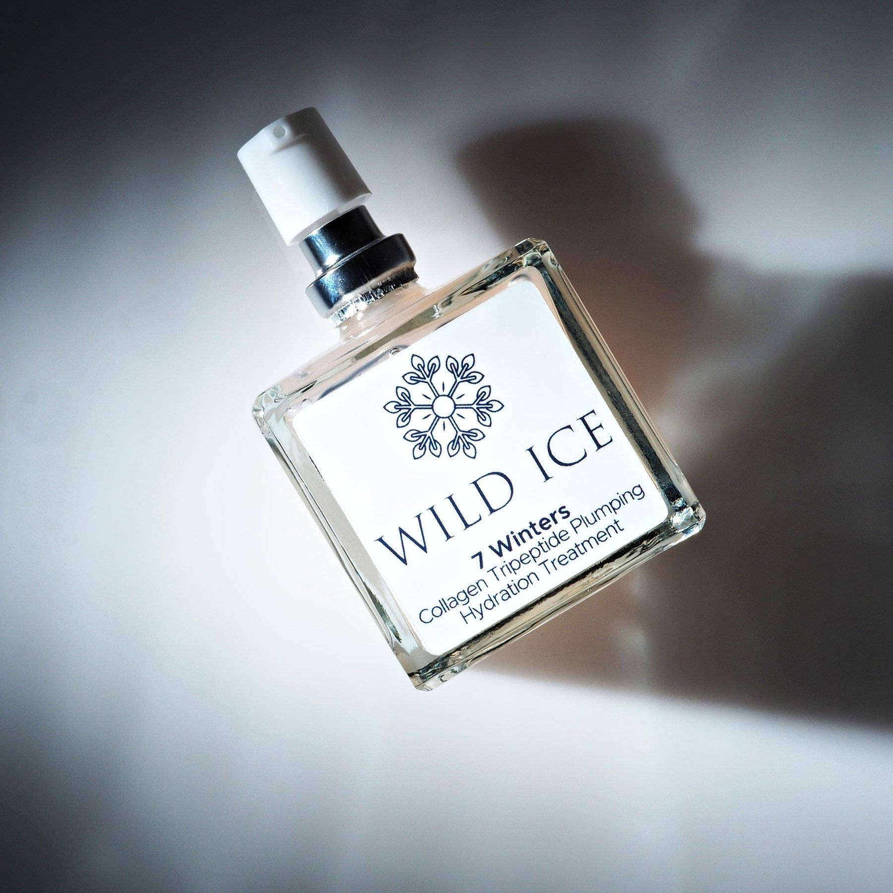 A bottle of 7 Winters collagen tripeptide serum lying on its side on a pale studio surface
