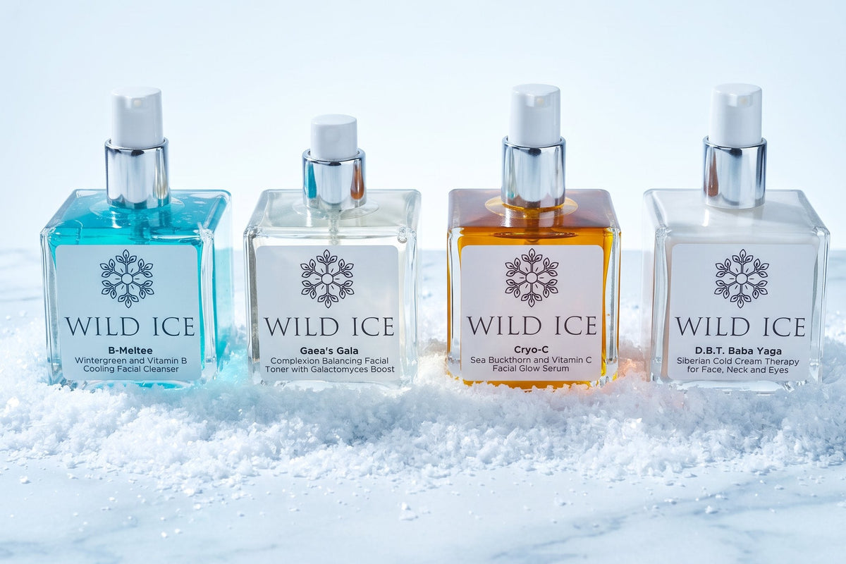 The four full-size Wild Ice Essentials Routine products standing in a row with their pumps uncovered, in snow on white marble