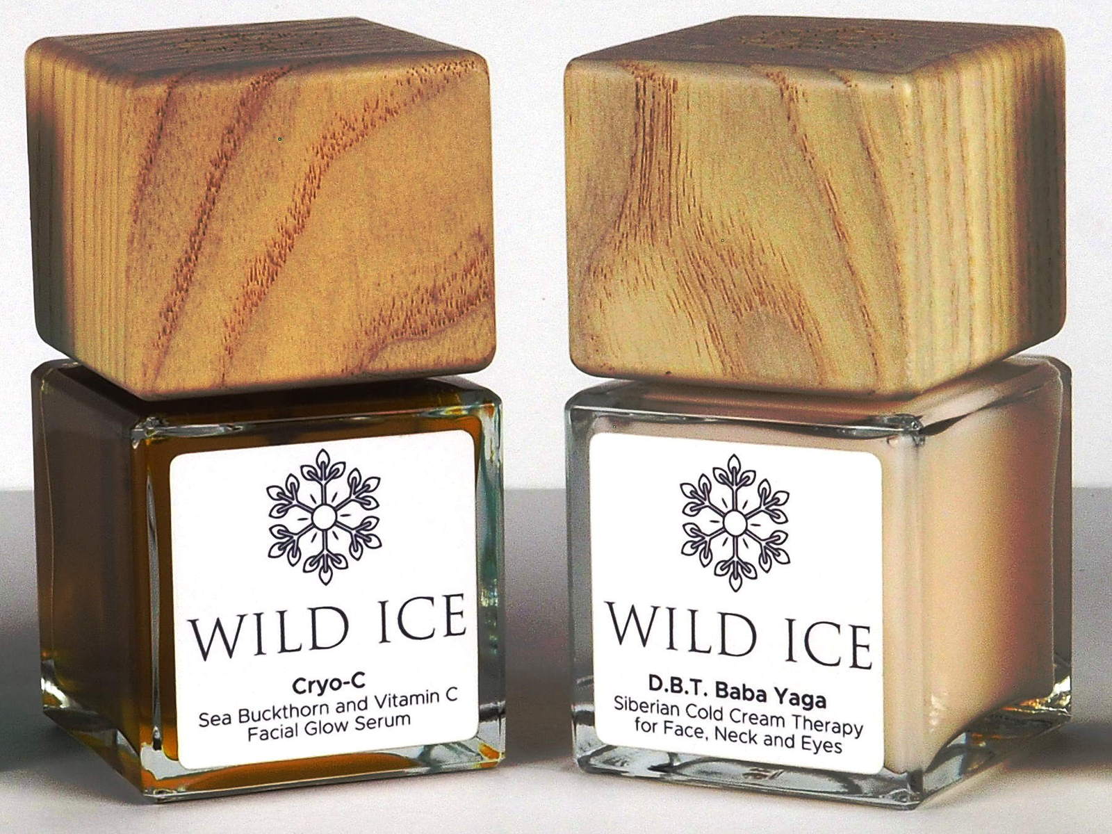 The Cryo-C vitamin C serum and the D.B.T. Baba Yaga cream side by side with their wood overcaps on, against a plain pale studio backdrop